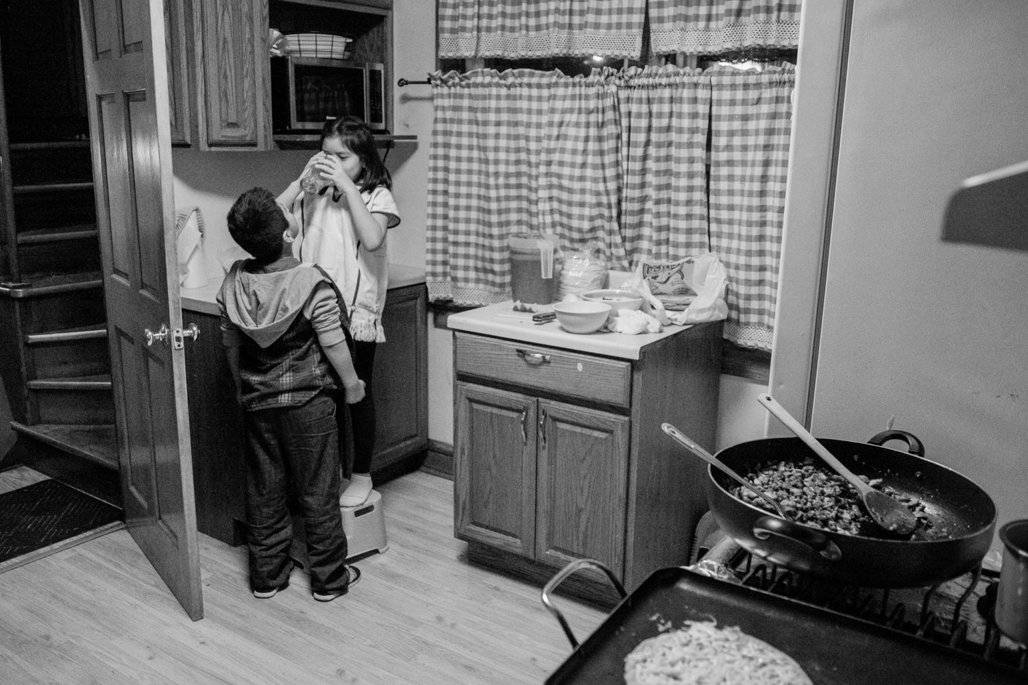 Mixe children hanging out in the kitchen with typical Mexican food on the stove. Milwaukee, Wisconsin, USA.